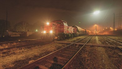 A red diesel locomotive stands on illuminated tracks at night, Ruhr area, North Rhine-Westphalia,