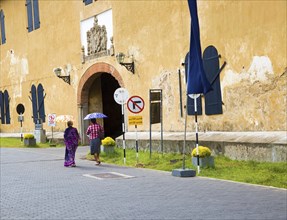 Women walking with umbrellas for shade towards the fort doorway exit in the historic town of Galle,