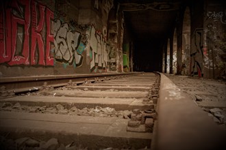 Railway tracks lead into the depths, accompanied by wall graffiti, former railway branch Rethel,