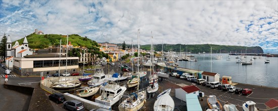 Wide angle shot of the harbour of Horta with boats, buildings and cars on the coastal road, Horta,