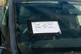 Abusive handwritten comment left on windscreen of car inconsiderately parked, UK