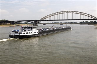 Barge beneath Waalbrug bridge, River Waal, Nijmegen, Gelderland, Netherlands