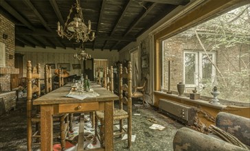 A damaged dining room with destroyed furniture and windows letting in daylight, Maison Limmi, Lost