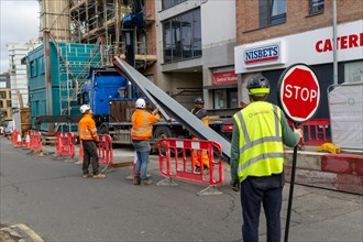 Workers and crane working with steel girder in street, Reading, Berkshire, England, UK
