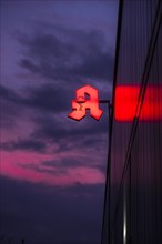 Illuminated pharmacy sign in front of a stormy sky on a facade in Duesseldorf, Germany, Europe