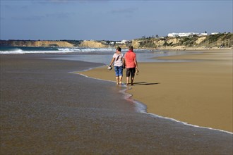 Man and woman walking together on sandy beach at Conil de la Frontera, Cadiz Province, Spain,