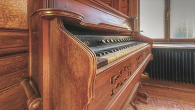 An old piano with open keyboard, surrounded by rich wood carving, Villa Woodstock, Lost Place,