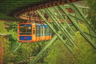 Blue and orange coloured suspension railway on a green track with steel construction, suspension