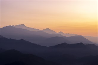 Silhouette of the Himalayan peaks, including Himalchuli and Baudha Himal, backlit by the orange