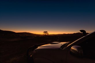 A car, jeep parked opposite a dramatic sunset in the wilderness, Namibia, Africa