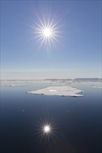 Midnight sun over the Arctic Ocean with drifting ice floes, north of the Arctic Circle at