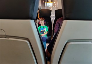 View of a young boy with headphones on a local train travelling through East Westphalia, Germany,