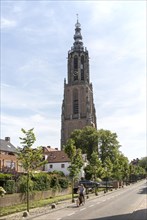 Woman cycling by Gothic church clock tower, Onze Lieve Vrouwetoren, Amersfoort, Netherlands