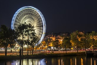 Motion blurred Ferris wheel at night along the Rhone river in the city Avignon, Vaucluse,