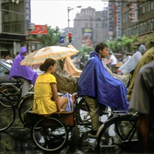 People on bicycles in the rain in the old town of Shanghai, China, Asia