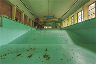 A dilapidated, empty swimming pool with rust stains on the floor, deserted atmosphere, Bad am Park,
