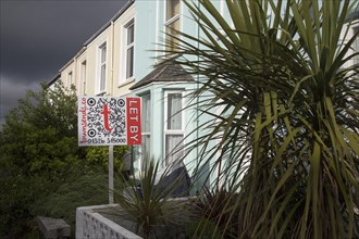 Terraced housing with letting signs in Falmouth, Cornwall, England, UK with storm clouds overhead