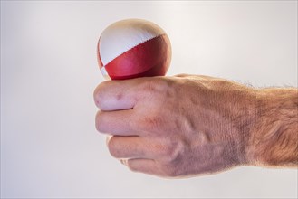 Hand with a juggling ball in front of a white background, studio shot, Germany, Europe