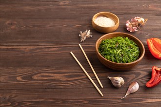 Chuka seaweed salad in wooden bowl on brown wooden background. Side view, copy space