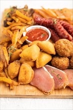 Set of snacks: sausages, fried potatoes, meat balls, dumplings, basturma on a cutting board on a