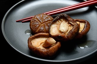 Dried and soaked shiitake mushrooms on a plate with chopsticks