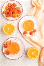 Papaya and orange jelly on gray concrete background and orange linen textile. top view, flat lay,