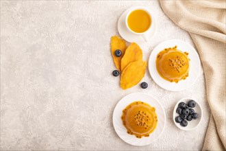 Mango and passion fruit jelly with blueberry on gray concrete background and linen textile. top