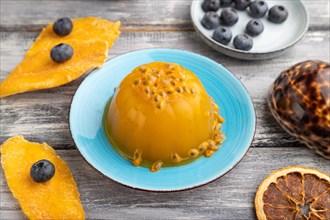 Mango and passion fruit jelly with blueberry on gray wooden background. side view, close up