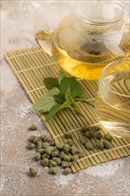 Green oolong tea with herbs in glass on brown concrete background. Healthy drink concept. Side