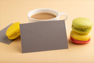 Gray paper business card mockup with yellow and green macaroons and cup of coffee on orange pastel