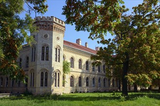 A historic Gothic-style castle surrounded by autumn trees under a clear blue sky, Officers' Palace,