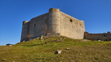 Ancient stone castle on a hill with green grass and clear blue sky, Chlemoutsi, High Medieval