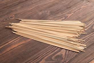 Japanese buckwheat soba noodles on brown wooden background. Side view, close up