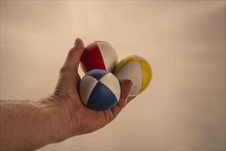 Male hand holding 3 colourful juggling balls, white background, studio shot, Germany, Europe