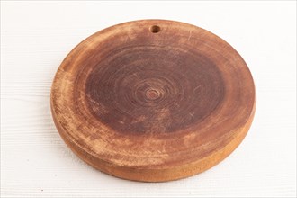 Empty round wooden cutting board on white wooden background. Side view, close up