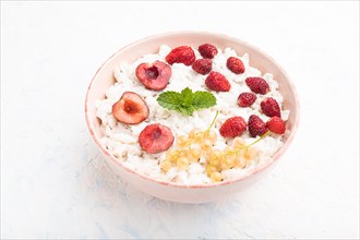 Rice flakes porridge with milk and strawberry in ceramic bowl on white concrete background. Side
