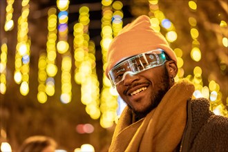 Cool african man wearing smart glasses in the city at night with lights decorating the streets