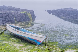 Small wooden boat in dry channel at low tide in Jeju, South Korea, Asia