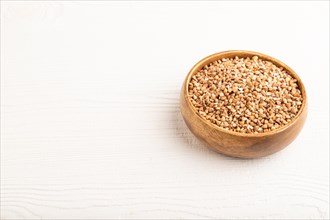 Raw buckwheat on white wooden background. Side view, copy space