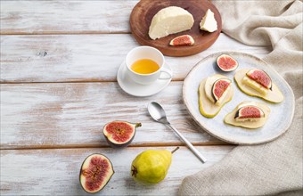 Summer appetizer with pear, cottage cheese, figs and honey on a white wooden background and linen