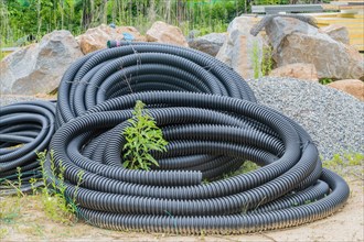 Black flexible pipe coiled and laying on ground at construction site