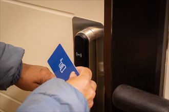 Cropped shot view of tourist woman using keycard to unlock an electronic door in luxury hotel