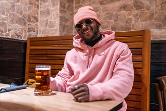 Portrait of a smiling cool african man in a bar drinking beer