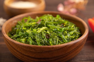 Chuka seaweed salad in wooden bowl on brown wooden background. Side view, close up, selective focus