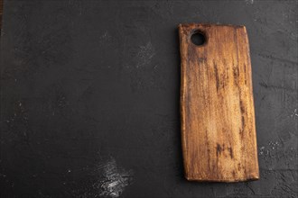 Empty rectangular wooden cutting board on black concrete background. Top view, copy space, flat lay