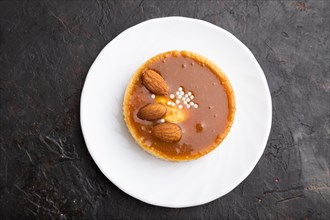 Sweet tartlets with almonds and caramel cream on a black concrete background. top view, flat lay,