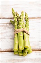 Bunch of fresh green asparagus on white wooden background. Side view, close up. harvest, healthy,