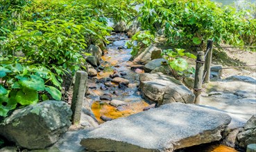 Small creek flowing under concrete footbridge in Japanese garden park in Hiroshima, Japan, Asia