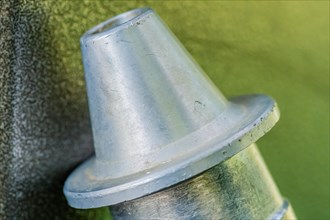 Closeup of triangle shaped flanged metal nozzle of air hose on blurred grayish green background