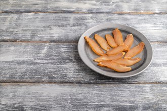Salted meat on a wooden plate on a gray wooden background. Side view, close up, copy space
